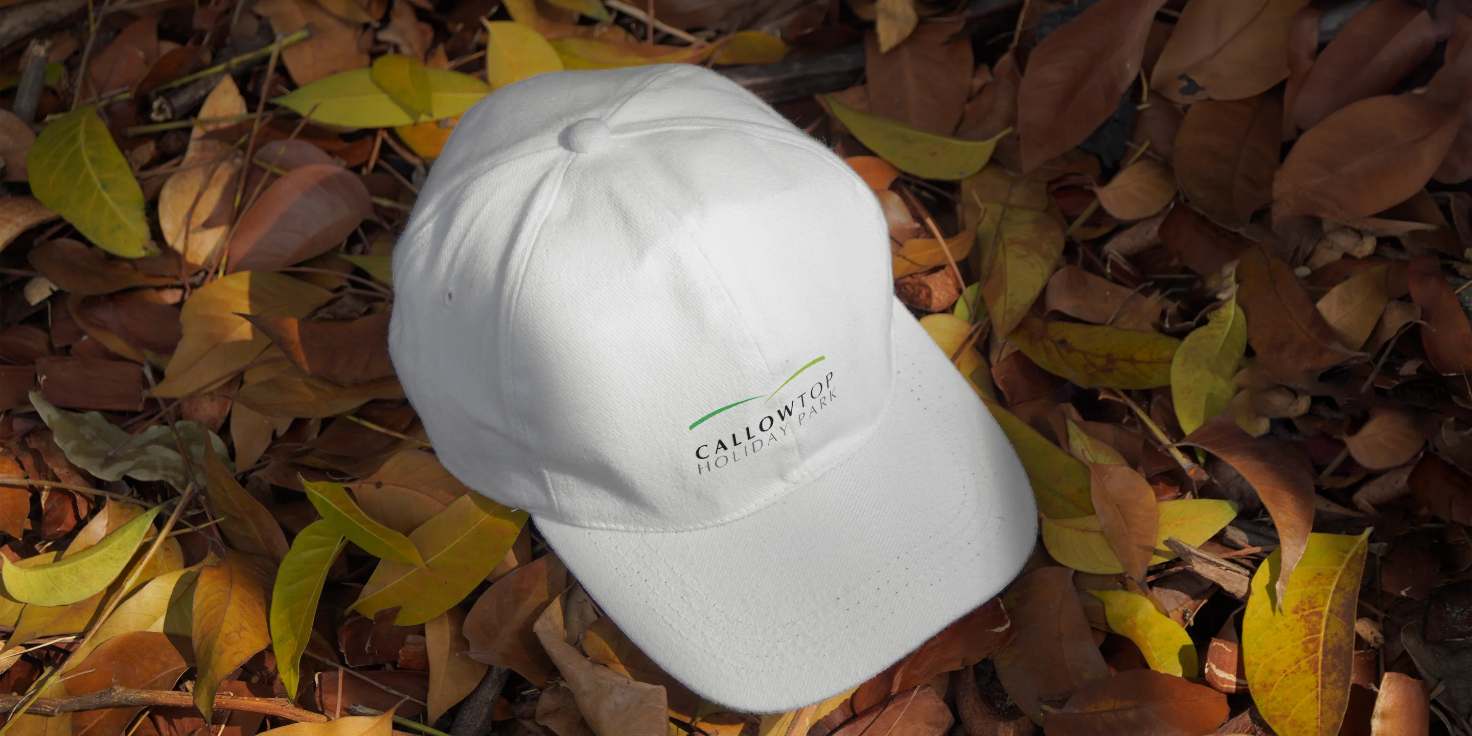 A Callow Top Holiday Park branded cap on autumn leaves