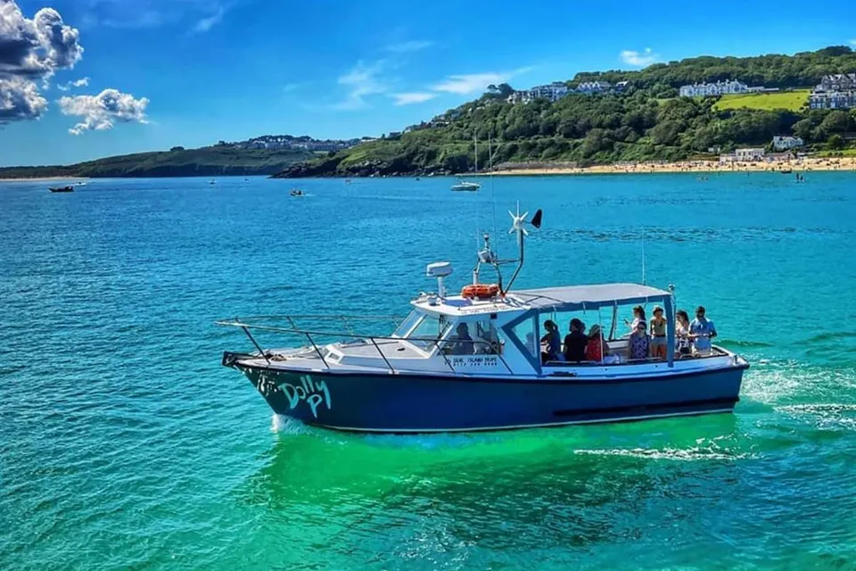 The Dolly P tour boat carrying passengers across turquoise water in St Ives bay