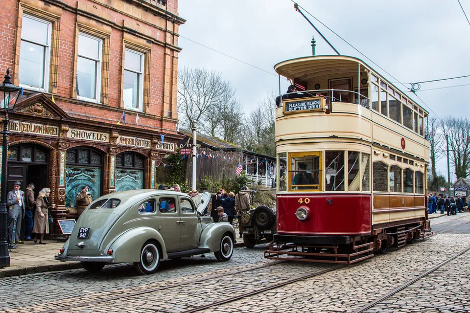A vintage double-decker tram passing the Red Lion pub at the National Tramway Museum in Crich, Derbyshire